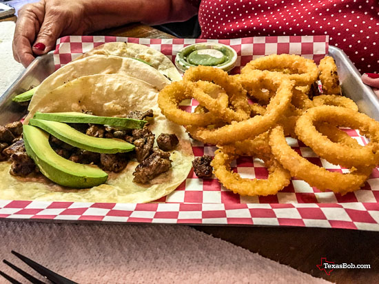 Rib-eye tacos with onion rings and avocado slices